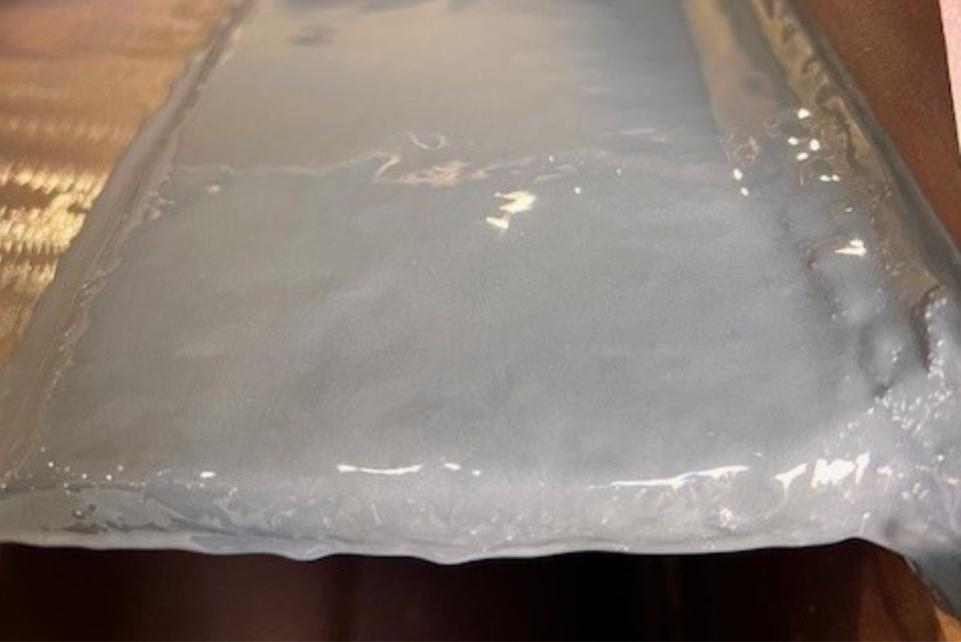 Close-up of a smooth, glossy greyish coating or sealant layer applied over a surface.