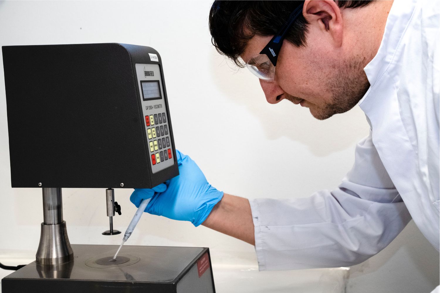 Muž v bílém plášti nanáší něco z pipety na povrch